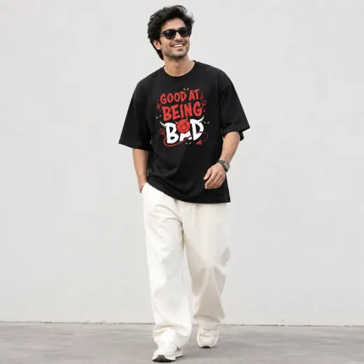 Oversized black t-shirt reading 'Good At Being Bad' with relaxed drop-shoulder fit