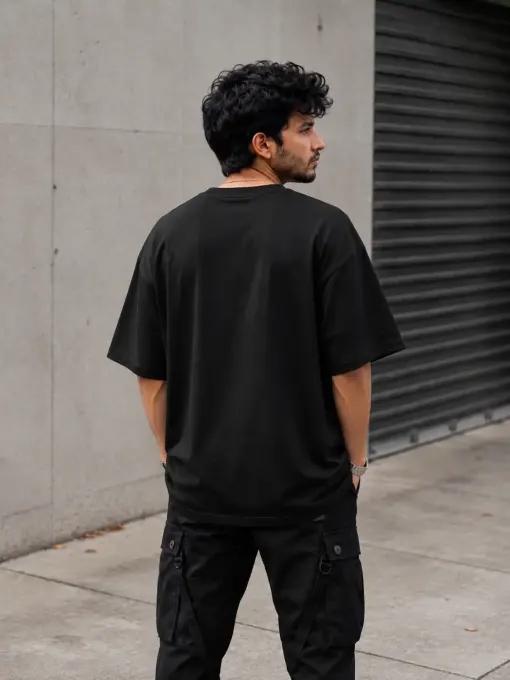 Black oversized t-shirt featuring a bold 'Nightmare' graphic on the front, relaxed short sleeves laid flat on a neutral background