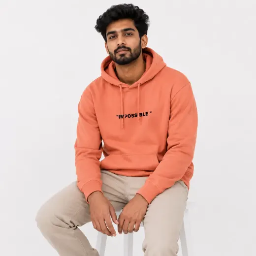Never Say Die coral pullover hoodie displayed on a plain background