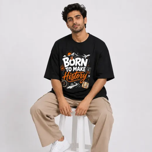 Model wearing black oversized T-shirt with 'Born To Make History' white chest print, relaxed fit crew neck